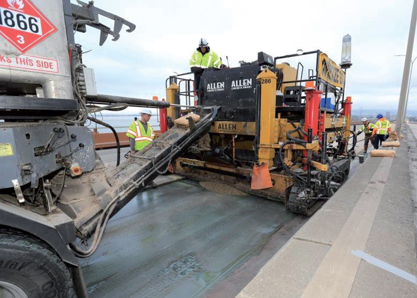 A continuous volumetric mixing/batching truck discharging polyester concrete into the paver (Courtesy of John Huseby, Caltrans).