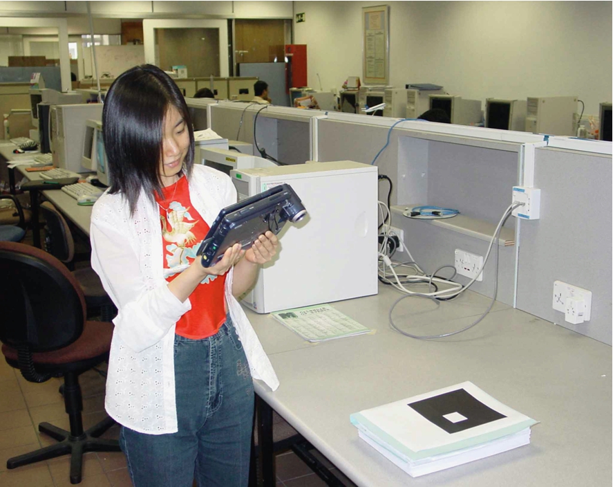 User viewing the remote object on her handheld device. The camera captures the image of the marker.
