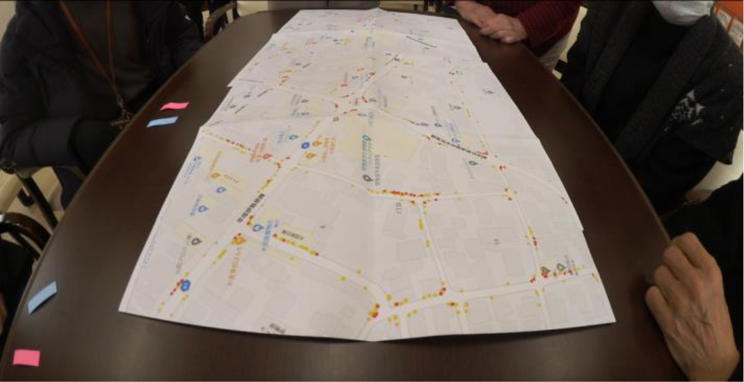Participants speaking around two maps during a task. The map in the foreground shows the proposed method.